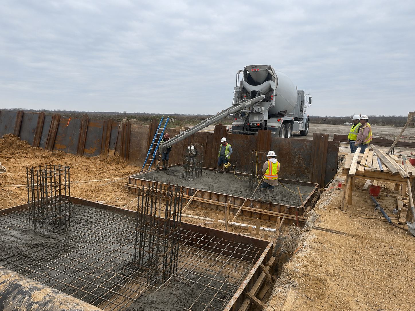GoldTex crew placing concrete for equipment foundations inside a sheet-piled excavation